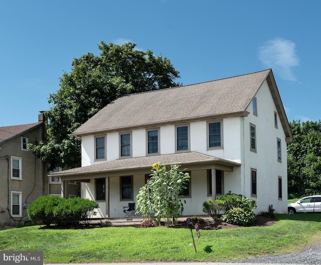 view of front of property with stucco siding, a porch, a front lawn, and a shingled roof