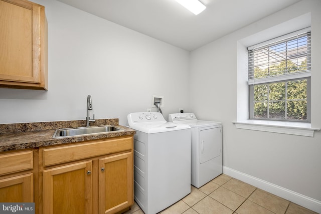 washroom featuring a sink, cabinet space, separate washer and dryer, light tile patterned floors, and baseboards