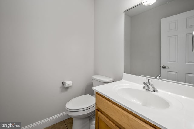 half bathroom featuring baseboards, toilet, vanity, and tile patterned flooring