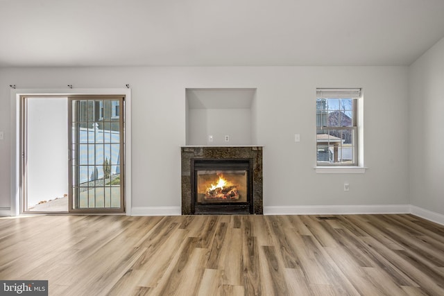 unfurnished living room with wood finished floors, baseboards, and a premium fireplace