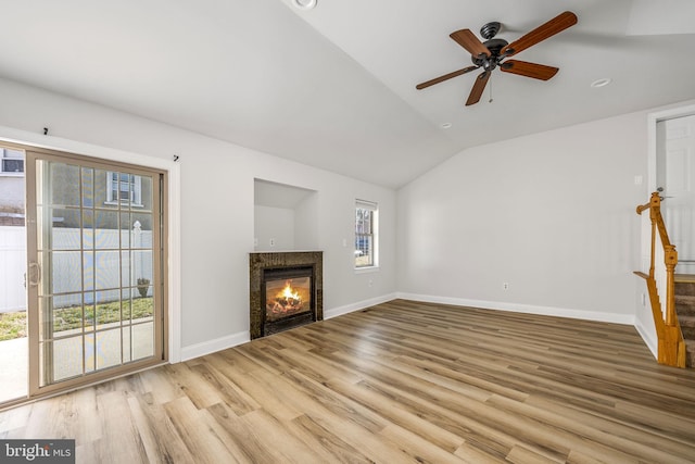 unfurnished living room with a ceiling fan, wood finished floors, baseboards, a fireplace, and vaulted ceiling