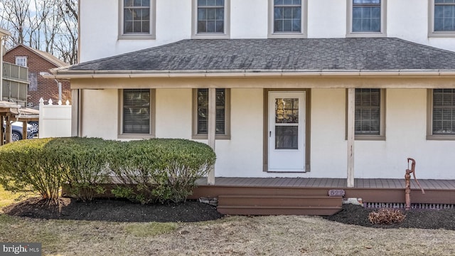 exterior space featuring stucco siding, covered porch, and a shingled roof