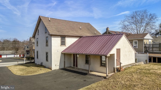 rear view of house featuring a yard, metal roof, and stucco siding