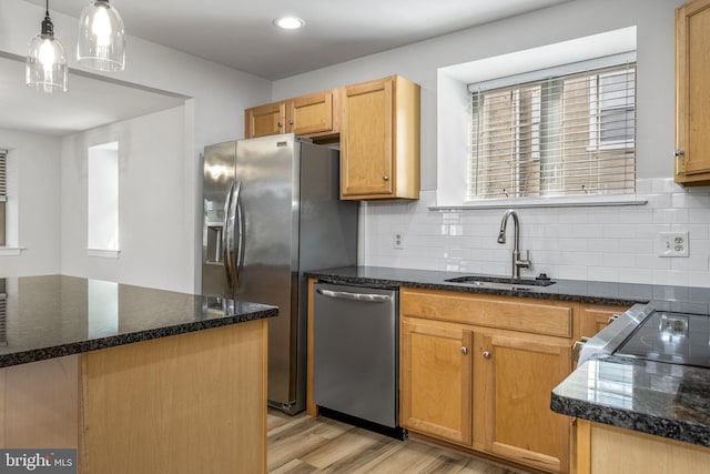 kitchen featuring plenty of natural light, dark stone countertops, appliances with stainless steel finishes, and a sink