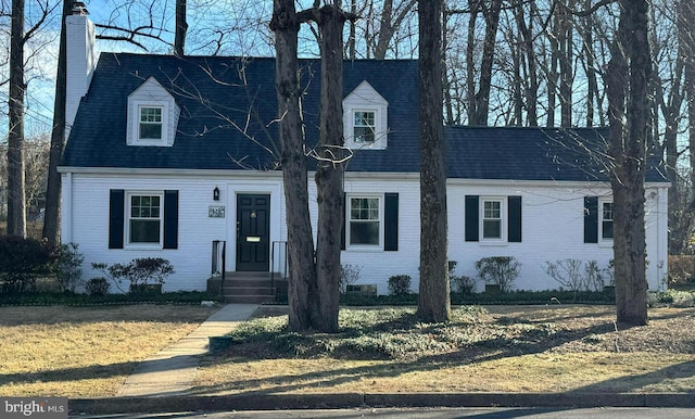 new england style home with crawl space, brick siding, and a chimney