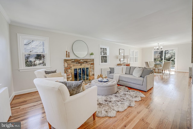 living area with crown molding, radiator heating unit, light wood-style floors, a stone fireplace, and baseboards