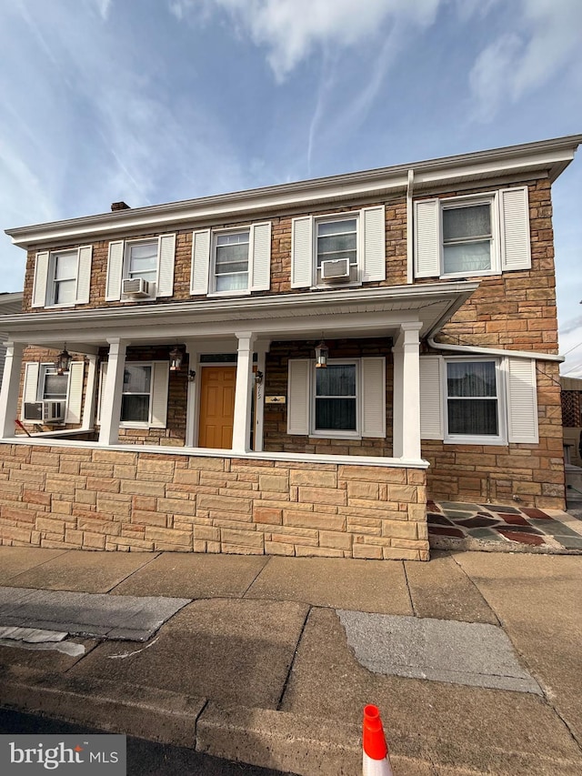 townhome / multi-family property featuring stone siding and a porch