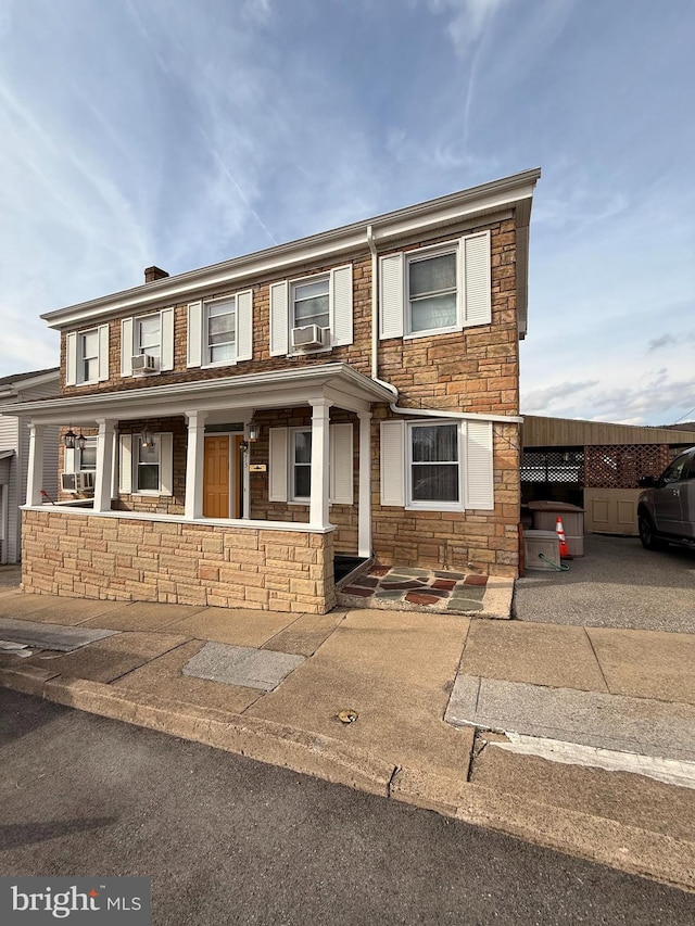 townhome / multi-family property featuring covered porch and stone siding