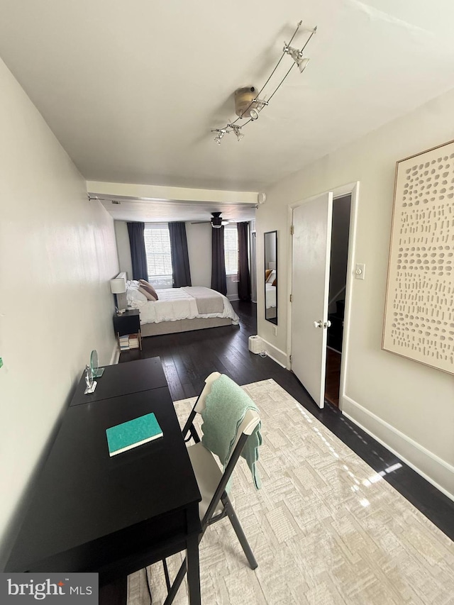 bedroom featuring rail lighting, baseboards, and dark wood-type flooring