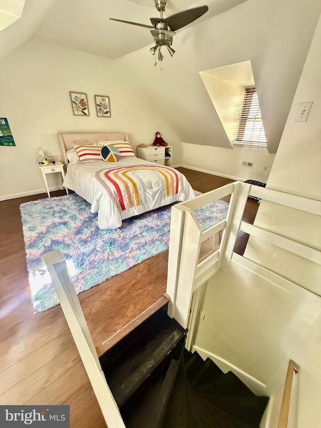 bedroom with ceiling fan, vaulted ceiling, and wood finished floors