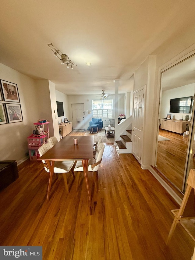 dining room featuring a ceiling fan, wood finished floors, and stairs