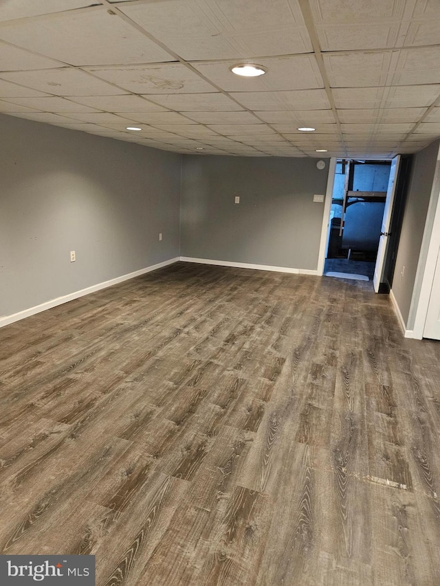 interior space with a paneled ceiling, baseboards, and wood finished floors