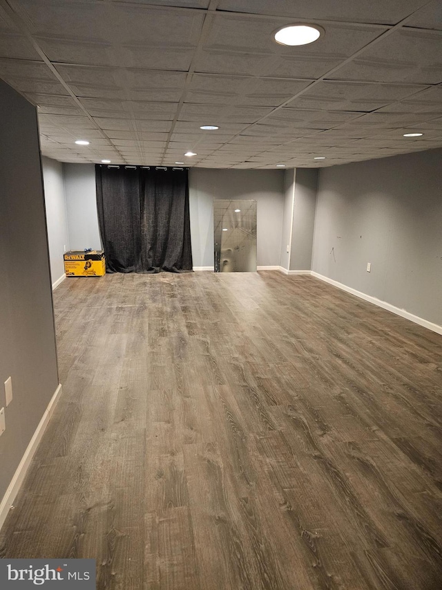 finished basement featuring wood finished floors, a paneled ceiling, and baseboards