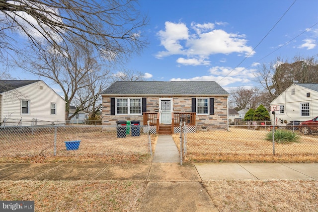 bungalow-style home featuring stone siding and a fenced front yard