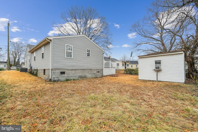 view of side of home featuring crawl space, a yard, and an outbuilding