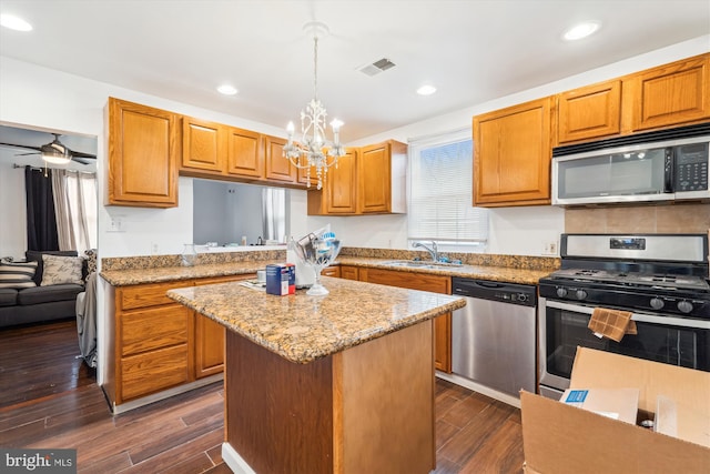 kitchen featuring visible vents, a kitchen island, appliances with stainless steel finishes, dark wood-type flooring, and a sink