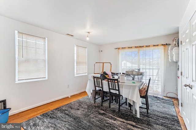 dining space with wood finished floors, visible vents, and baseboards