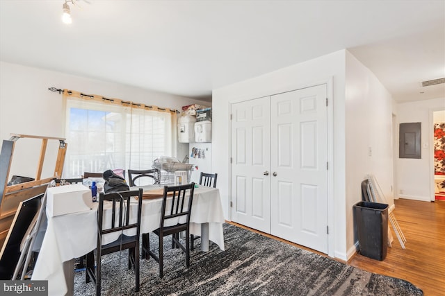 dining space with baseboards, electric panel, visible vents, and wood finished floors