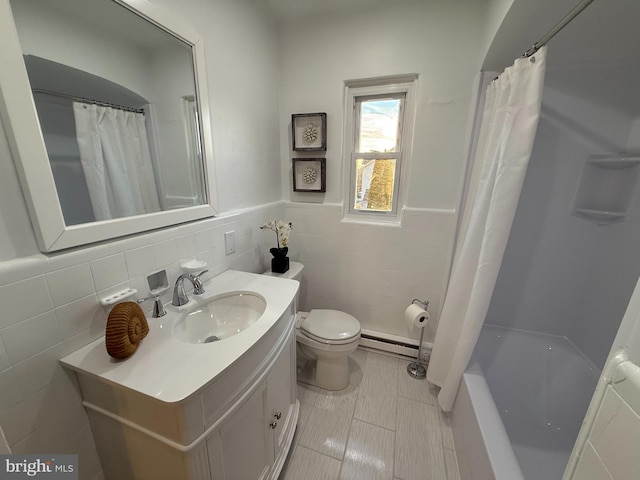 full bath with tile walls, a baseboard radiator, toilet, wainscoting, and vanity