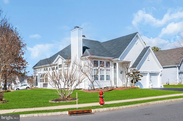 view of front of property featuring a shingled roof, driveway, a chimney, and a front lawn