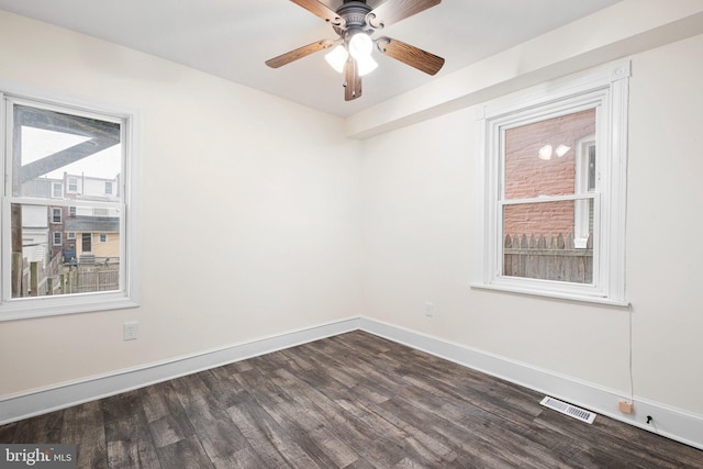 spare room featuring dark wood-style floors, visible vents, baseboards, and a ceiling fan