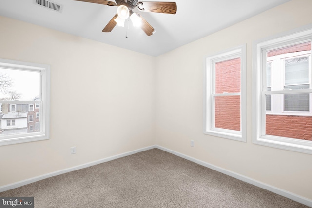 carpeted spare room with a ceiling fan, visible vents, and baseboards