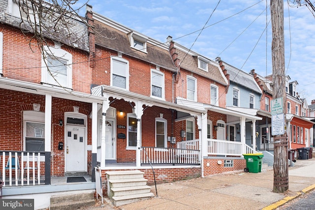 townhome / multi-family property featuring a porch and brick siding