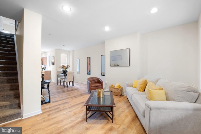 living area with light wood-type flooring, baseboards, stairway, and recessed lighting