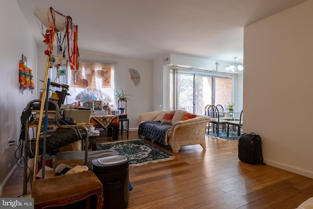 living area featuring a wealth of natural light, a notable chandelier, baseboards, and wood finished floors