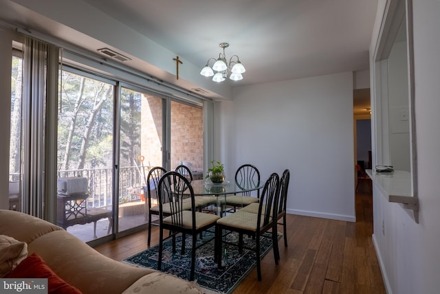 dining space featuring wood-type flooring, visible vents, a chandelier, and baseboards