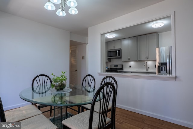 dining room featuring baseboards, a chandelier, and wood finished floors