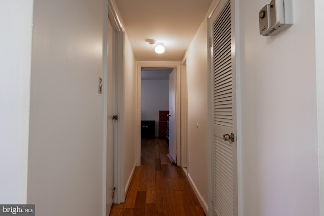 hallway featuring baseboards and dark wood finished floors