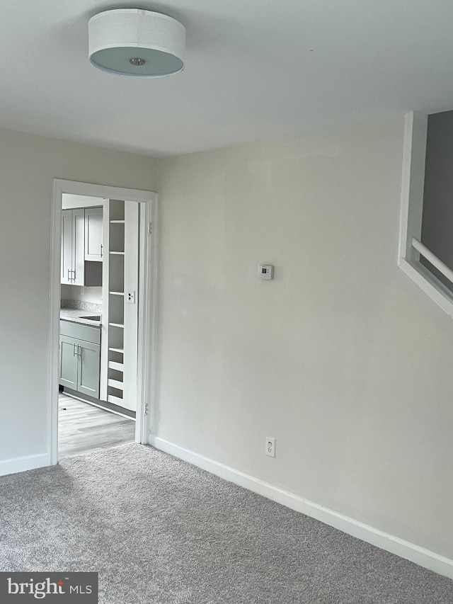 spare room with light carpet and baseboards