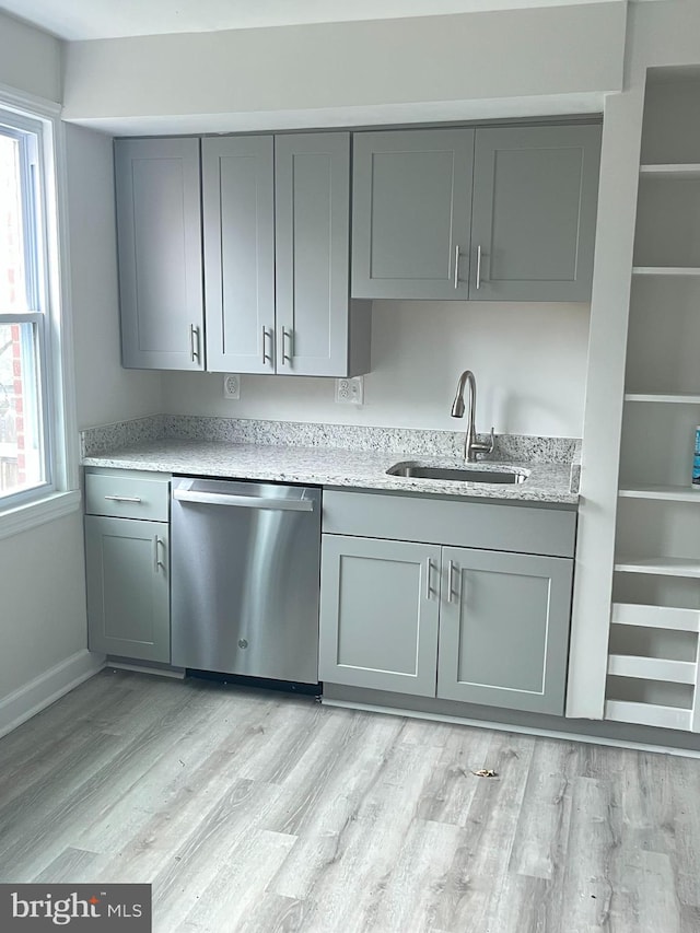 kitchen featuring dishwasher, gray cabinets, a sink, and light wood-style floors