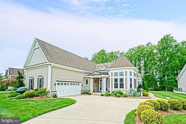 view of front of home with driveway, a shingled roof, and a front lawn