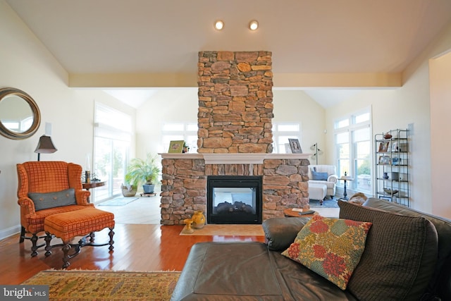 living room featuring lofted ceiling with beams, a fireplace, wood finished floors, and plenty of natural light