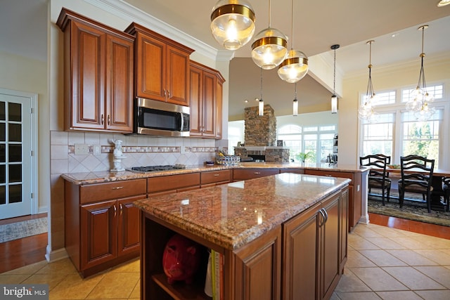 kitchen featuring a center island, crown molding, stainless steel appliances, decorative backsplash, and light stone countertops