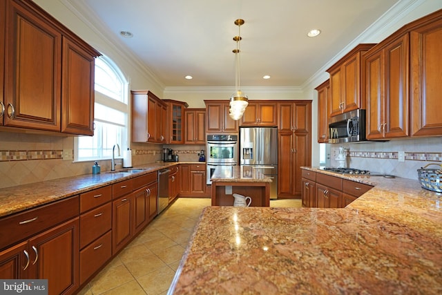 kitchen featuring light stone counters, stainless steel appliances, a sink, hanging light fixtures, and brown cabinetry