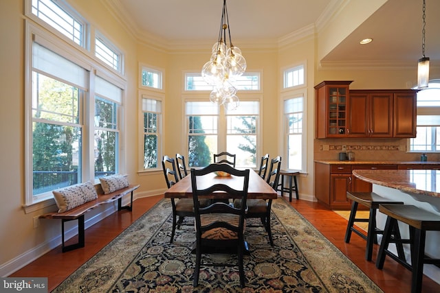 dining room with ornamental molding, dark wood-type flooring, baseboards, and an inviting chandelier