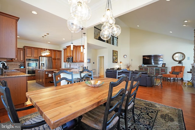 dining space with high vaulted ceiling, ornamental molding, light wood-type flooring, and recessed lighting