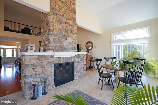 living area with high vaulted ceiling, a fireplace, and tile patterned flooring