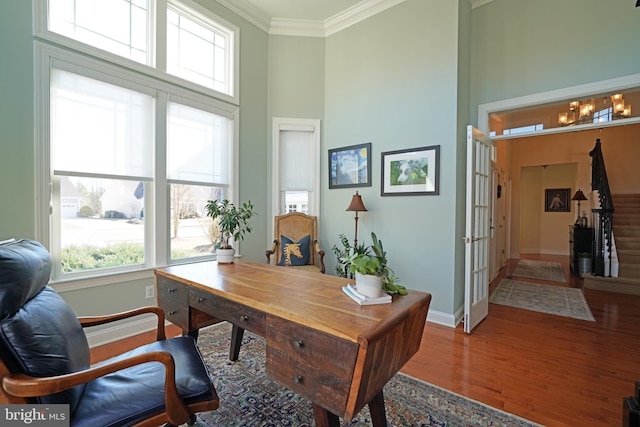 home office featuring baseboards, a high ceiling, ornamental molding, and wood finished floors