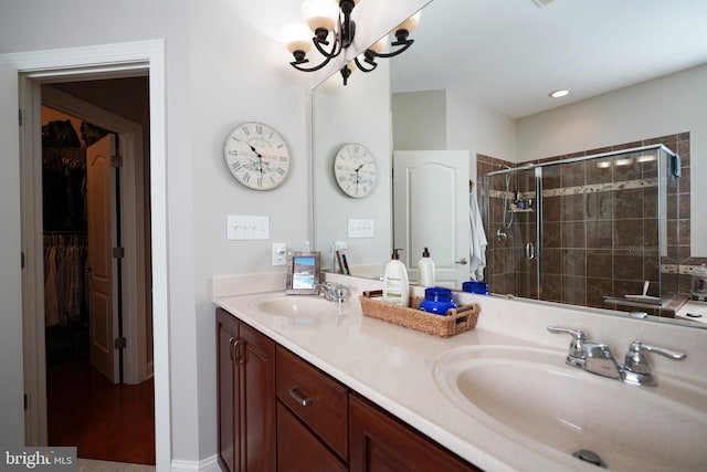 full bath featuring double vanity, a spacious closet, a sink, and a shower stall