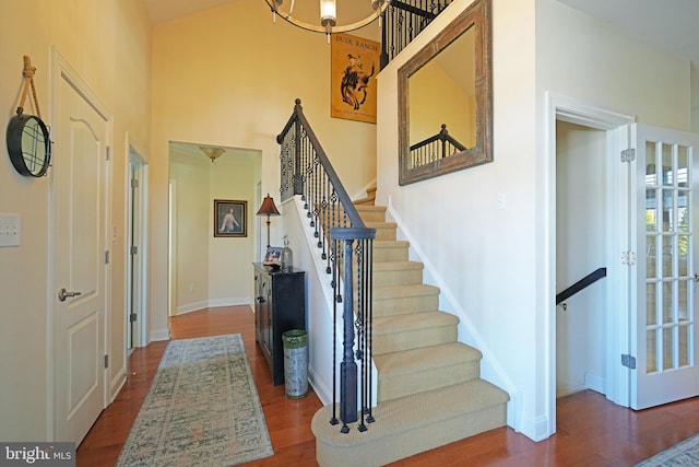 foyer entrance featuring stairs, a high ceiling, baseboards, and dark wood-style flooring