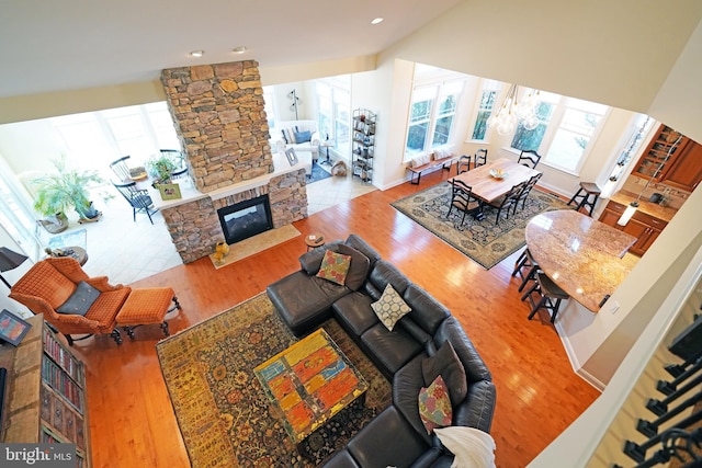 living area featuring lofted ceiling, recessed lighting, a stone fireplace, and wood finished floors