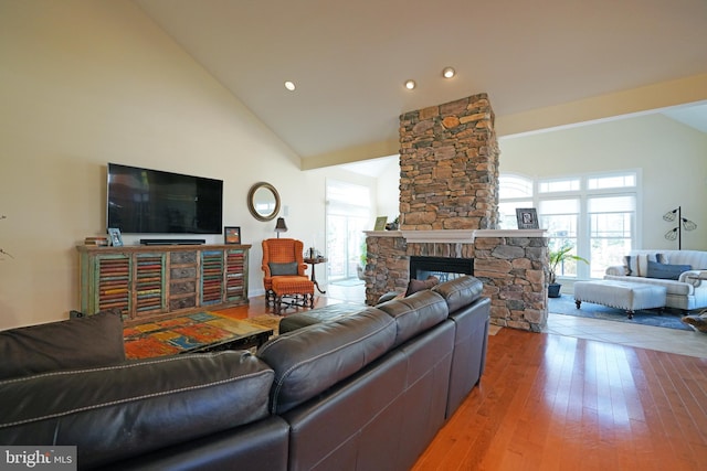 living room featuring high vaulted ceiling, hardwood / wood-style floors, a fireplace, and recessed lighting