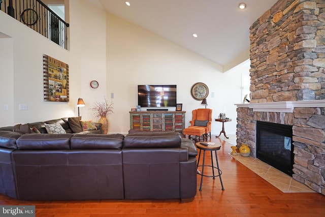 living area featuring high vaulted ceiling, recessed lighting, a fireplace, and wood finished floors