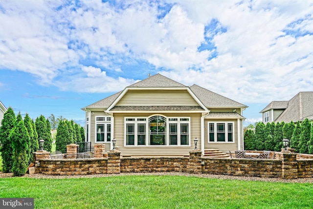 rear view of house with a shingled roof, a lawn, and a gambrel roof