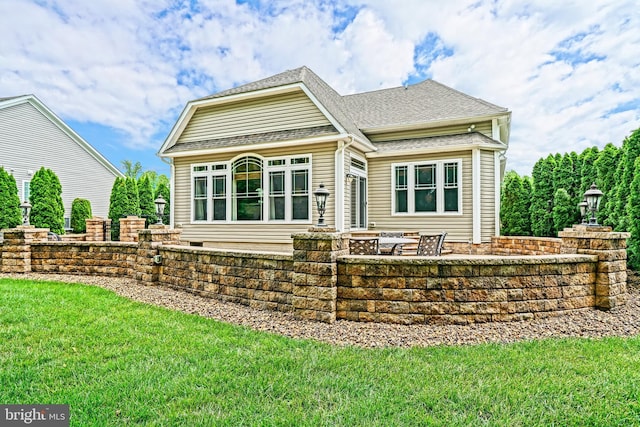 rear view of house featuring a patio area, a yard, and roof with shingles