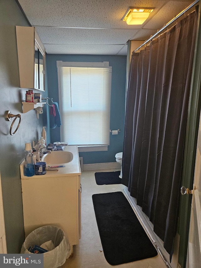 full bath featuring curtained shower, a drop ceiling, vanity, and toilet